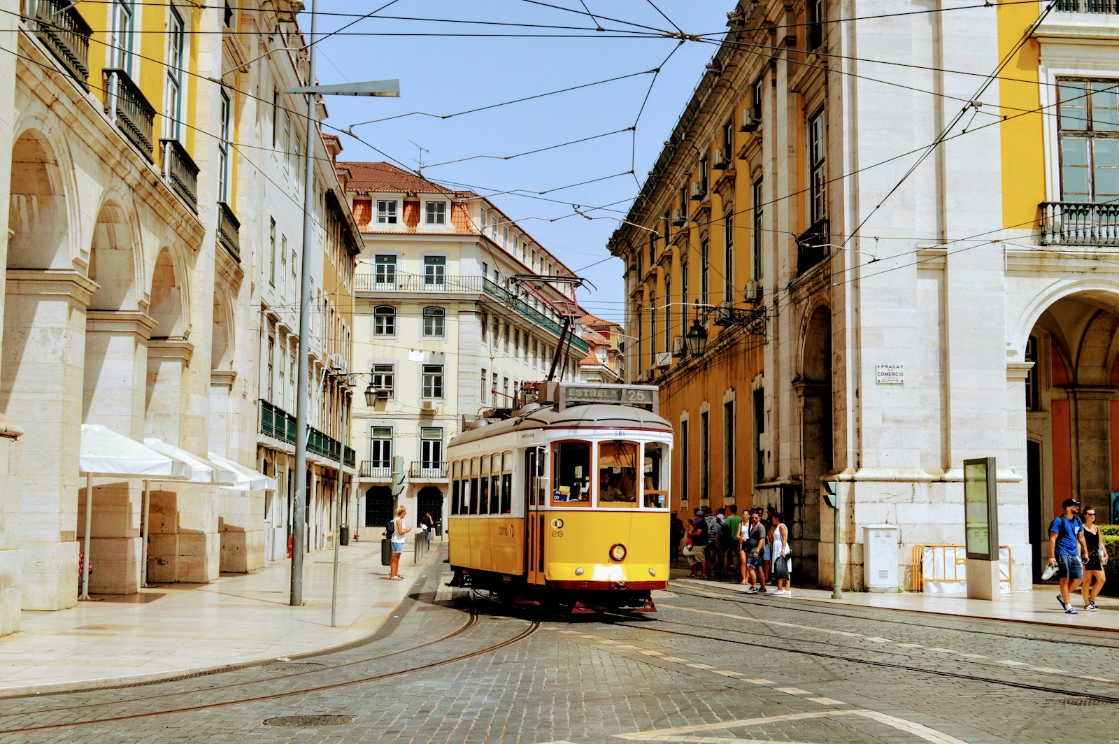 A yellow tram on a street of old buildings in Lisbon